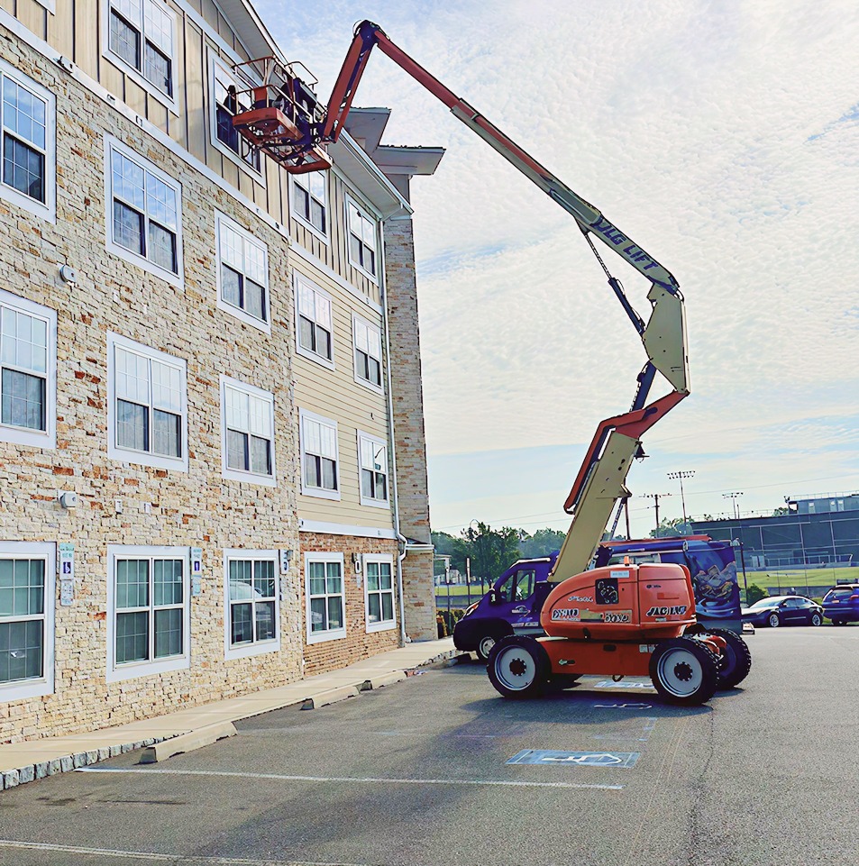 Red aerial lift platform extending up the side of a multi-story building for duct cleaning maintenance